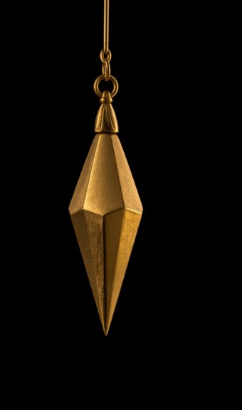 A brass dowsing pendulum hanging on its chain against a black background